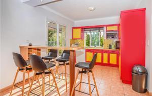 a kitchen with red and yellow cabinets and bar stools at Nice Home In Algajola With 3 Bedrooms And Wifi in Algajola