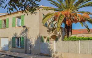 a building with a palm tree next to a fence at Cozy Home In Algajola With Kitchen in Algajola