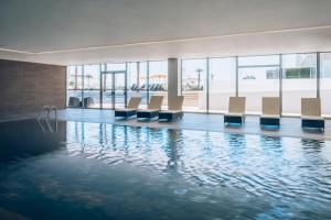 - une piscine avec des chaises dans un bâtiment dans l'établissement Iberostar Selection Lagos Algarve, à Lagos