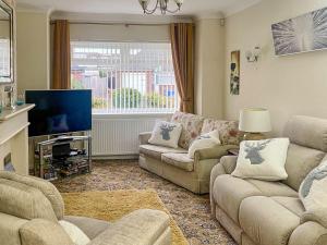 a living room with two couches and a flat screen tv at The Bay Cottage in Thornton