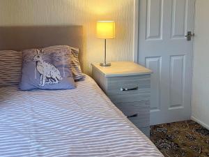 a bedroom with a bed and a lamp on a night stand at The Bay Cottage in Thornton