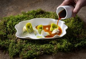 a person holding a cup of coffee and a plate of food at Klosterhof – Alpine Hideaway & Spa in Bad Reichenhall