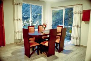 ein Esszimmer mit einem Tisch, Stühlen und einem Fenster in der Unterkunft Casa de Campo - Baños de Agua Santa in Juivi