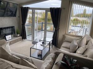 ein Wohnzimmer mit einem Sofa und einem Tisch in der Unterkunft Sunrise - Beautiful lakeside caravan in South Cerney