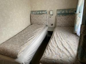 two beds sitting next to each other in a room at Sunrise - Beautiful lakeside caravan in South Cerney
