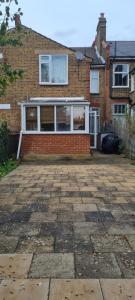 a brick house with a large patio in front of it at George Lane in London