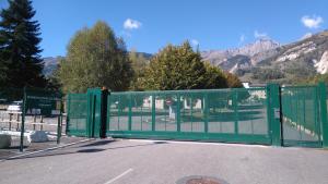 a green gate with a mountain in the background at 1 Bedroom flat, 5 min walk funicular Les Arcs & in city center, Parking, Wifi in Bourg-Saint-Maurice