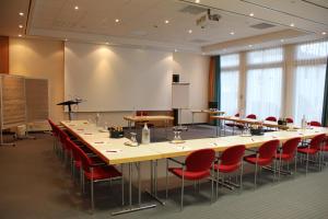 uma sala de conferências com uma mesa longa e cadeiras vermelhas em Hotel Villa Dürkopp em Bad Salzuflen