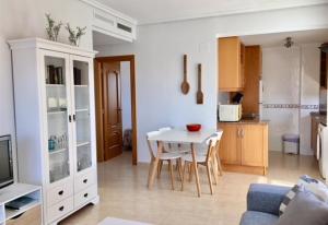 Una cocina y una sala de estar con una mesa y sillas blancas. en Cozy bright apartment, en Guardamar del Segura