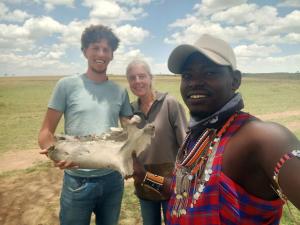 two men and a woman holding a skull in a field at Sonkoi Tent Safari Camp in Narok +10 photos