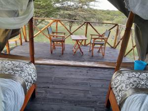 a porch with two beds and chairs on a deck at Sonkoi Tent Safari Camp in Narok