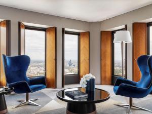 uma sala de estar com duas cadeiras azuis e uma mesa de vidro em Sofitel Melbourne On Collins em Melbourne