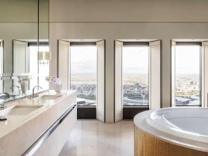 a bathroom with two sinks and a tub with windows at Sofitel Melbourne On Collins in Melbourne