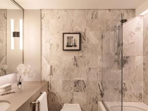 a bathroom with a shower and a toilet and a sink at Sofitel Melbourne On Collins in Melbourne