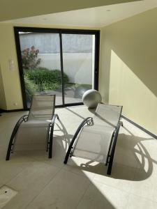 2 sillas sentadas en una habitación con ventana en Studio cosy avec en option piscine accessible de avril à octobre, en Quimperlé