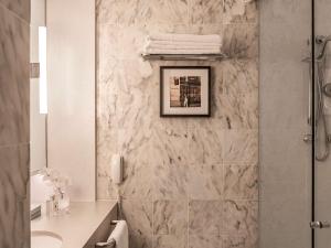 a bathroom with a shower and a marble wall at Sofitel Melbourne On Collins in Melbourne