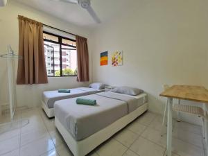 two beds in a bedroom with a table and a desk at MG Mutiara Gurney in George Town