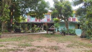 a house in the middle of a yard with trees at Tahan Guest House in Kuala Tahan