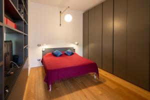a bedroom with a bed with a red blanket and blue pillows at Fleming Magnolia, confortevole open space in Rome