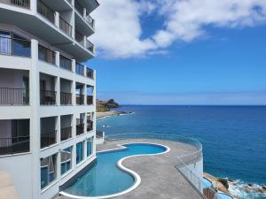 - un bâtiment avec une piscine à côté de l'océan dans l'établissement Hotel Royal Orchid, à Caniço