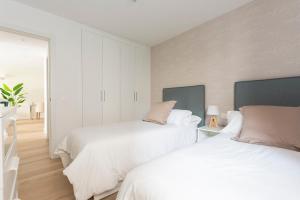 two beds in a bedroom with white walls and wood floors at The Terraces Luxury Penthouses, 1D in Santa Cruz de Tenerife
