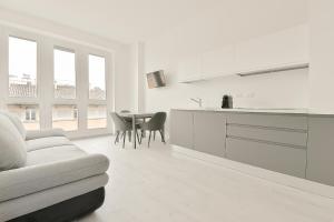 a white kitchen with a couch and a table at Milleventi Apartments in Bologna