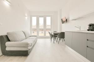Milleventi Apartments في بولونيا: غرفة معيشة بيضاء مع أريكة وطاولة
