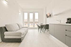 ein weißes Wohnzimmer mit einer Couch und einem Tisch in der Unterkunft Milleventi Apartments Bologna in Bologna