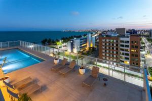 a rooftop deck with a swimming pool and the ocean at Acqua Residences Luxury Collection in Cabedelo