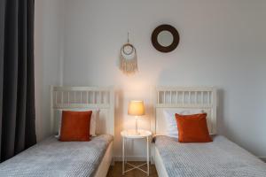 2 camas con almohadas de color naranja en un dormitorio en Pure Home Apartments - Gwiaździsta, en Wroclaw