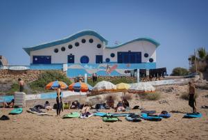 grupa ludzi leżących na plaży z parasolami w obiekcie Fleur de cactus, Guesthouse, Tamraght w mieście Agadir