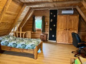 um quarto num chalé de madeira com uma cama e uma cadeira em Domwigierski pl -Tobołowo GR -nad samym brzegiem jeziora z sauną- klimatyzacja em Tobołowo