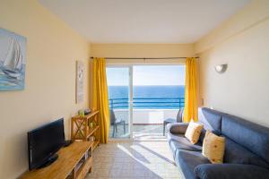 Una sala de estar con un sofá azul y un televisor. en Apto en Primera Línea Arenal Calpe, en Calpe