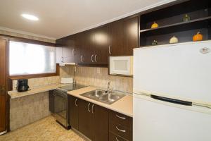 Una cocina con fregadero y refrigerador blanco. en Apto en Primera Línea Arenal Calpe, en Calpe