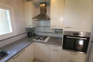uma cozinha com armários brancos e um forno com placa de fogão em Villa Las Hiertas - 6-8 personnes - vue mer em Alcossebre