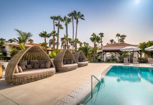 un complejo con una piscina con sillas de mimbre y un complejo en Barceló Fuerteventura Royal Level - Adults Only en Caleta de Fuste