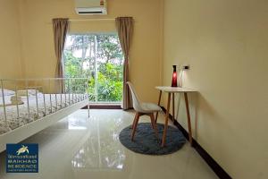 a room with a chair and a table and a window at MaiKhao Residence in Mai Khao Beach