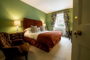 a bedroom with a bed and a chair and a window at High Force Hotel in Newbiggin