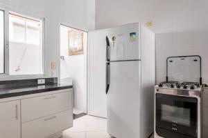 uma cozinha branca com um frigorífico e um fogão em Juquehy - Casa Espaçosa em Condomínio em Juqueí