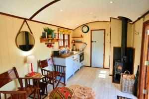 uma cozinha com uma mesa, cadeiras e um fogão em Finest Retreats - Maple Luxury Shepherds Hut em Dittisham