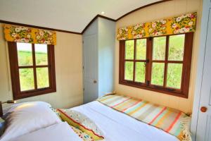 um quarto com uma cama e duas janelas em Finest Retreats - Maple Luxury Shepherds Hut em Dittisham