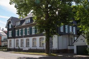 une grande maison blanche avec un arbre en face dans l'établissement 2T Hotel artgenossen, à Lindlar