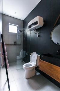 uma casa de banho com um WC, um chuveiro e um lavatório. em The Banyu House em Bandung