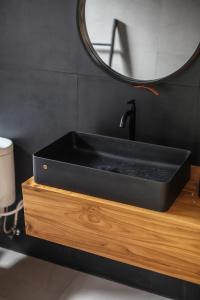 - un lavabo noir sur un comptoir en bois avec un miroir dans l'établissement The Banyu House, à Bandung