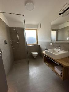 uma casa de banho com um lavatório, um chuveiro e um WC. em Appart Anna em Scheffau am Wilden Kaiser