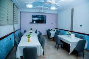 a dining room with tables and chairs and a tv at Best Lodge in Tamale