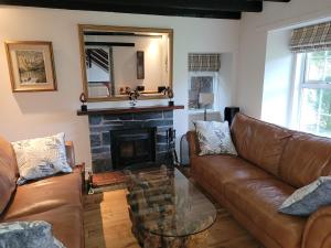 - un salon avec un canapé et une cheminée dans l'établissement Dubh Loch Cottage, à Rowardennan