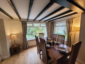 d'une salle à manger avec une table, des chaises et une fenêtre. dans l'établissement Dubh Loch Cottage, à Rowardennan