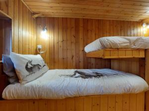 sypialnia z 2 łóżkami piętrowymi w drewnianej ścianie w obiekcie Sweet Somma Mountain Lodge 2 w mieście San Guglielmo