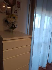 a dresser with a vase of flowers and a window at B&B Giulio Cesare in Vasto